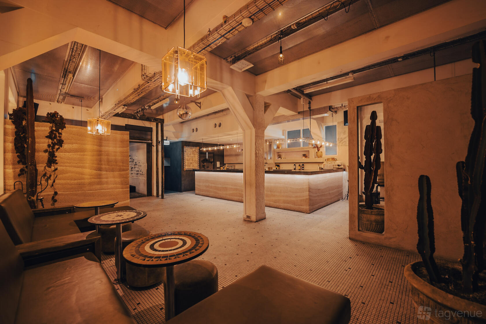 A live music venue with a spacious tiled floor, lounge seating, round mosaic tables, and pendant lighting at Alcatraz Sydney.