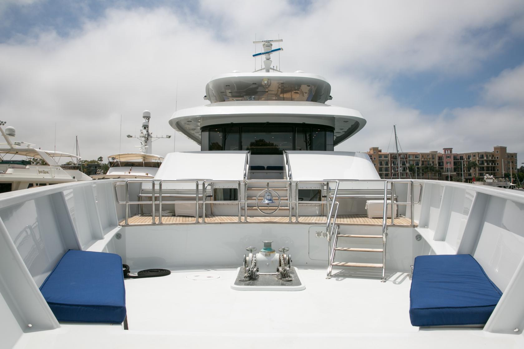 A yacht deck with blue cushioned benches, stainless steel railings, and marina views at Leight Star Yacht.