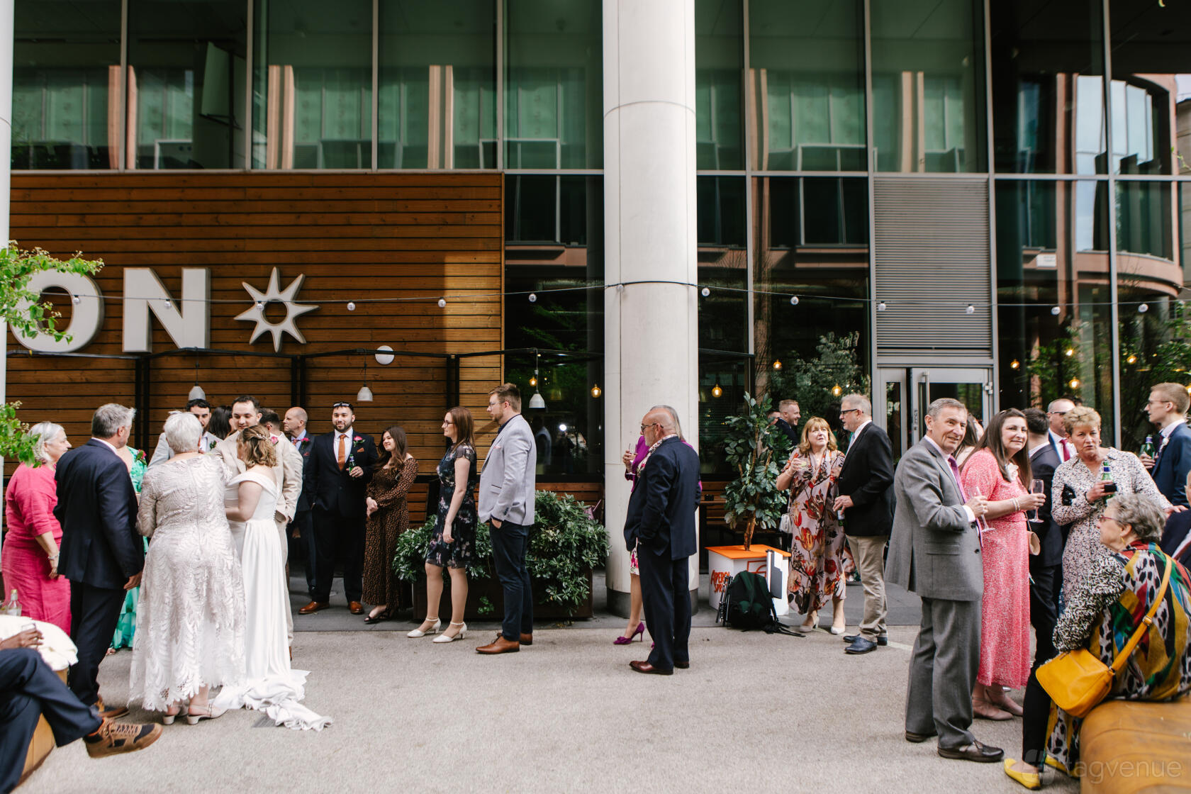An outdoor event space with modern wood paneling, tall columns, and groups of people socializing at The Union Regents.