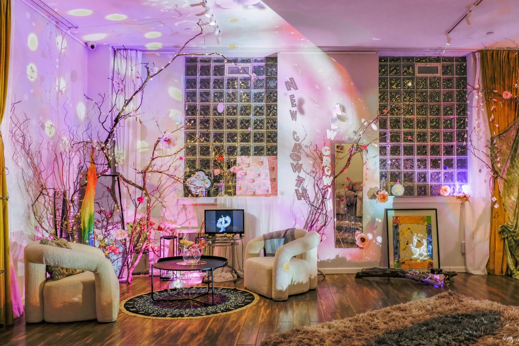 An event space with lounge chairs, decorative branches, and colorful lighting effects at The Modernist Hotel.