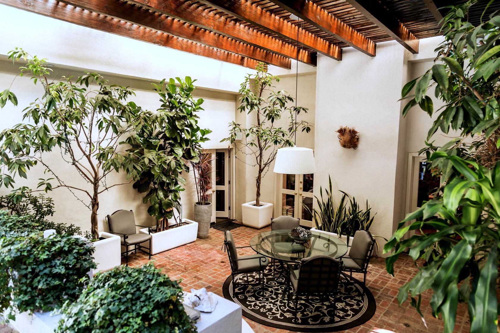 A house with a covered patio, brick flooring, potted trees, and a round glass table at Devlin House.