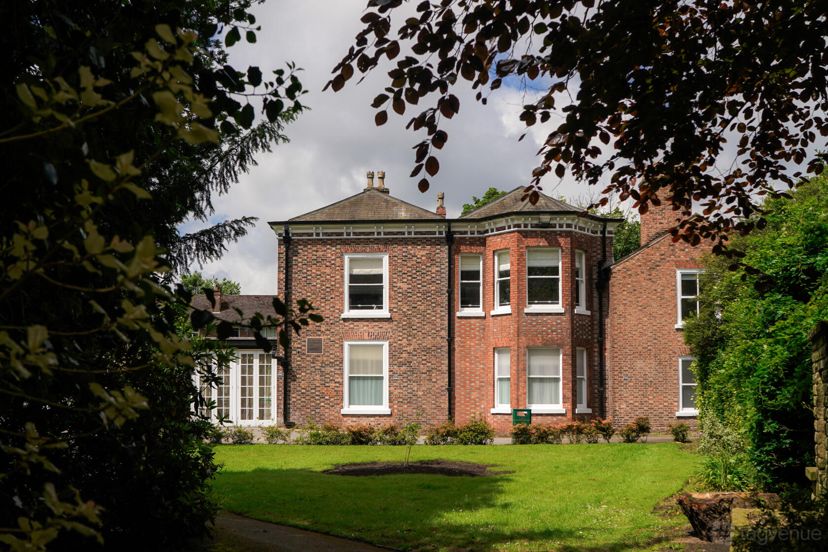 A historic building with red brick exterior, large bay windows, and manicured lawns at Flixton House.