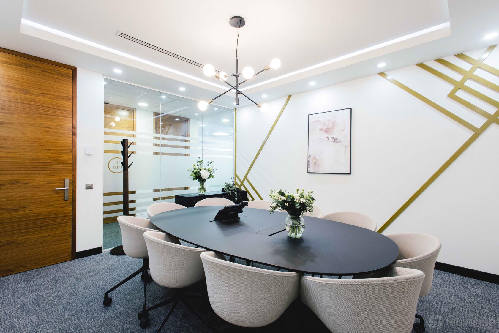A meeting centre with an oval table, white chairs, floral centerpieces, and geometric wall accents at Orega Bristol.
