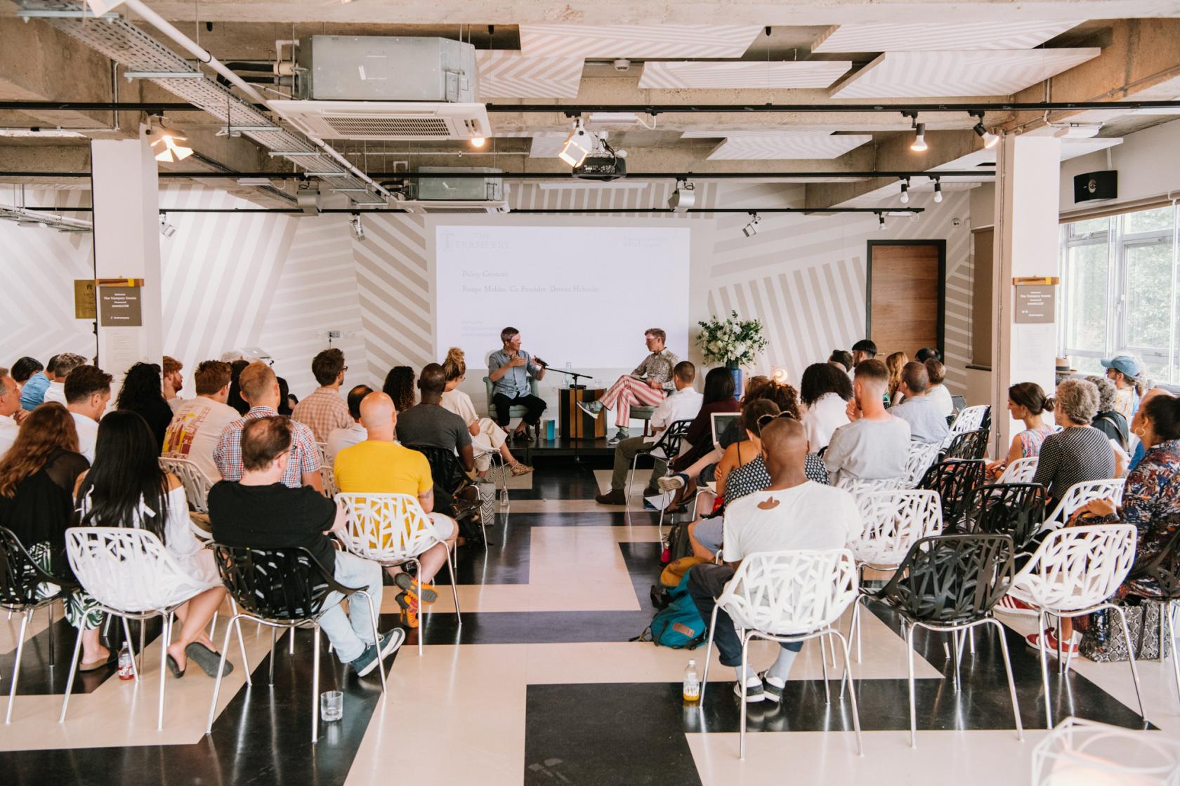 An event space with geometric-patterned floors, modern chairs, and a projection screen at The Trampery Old Street.