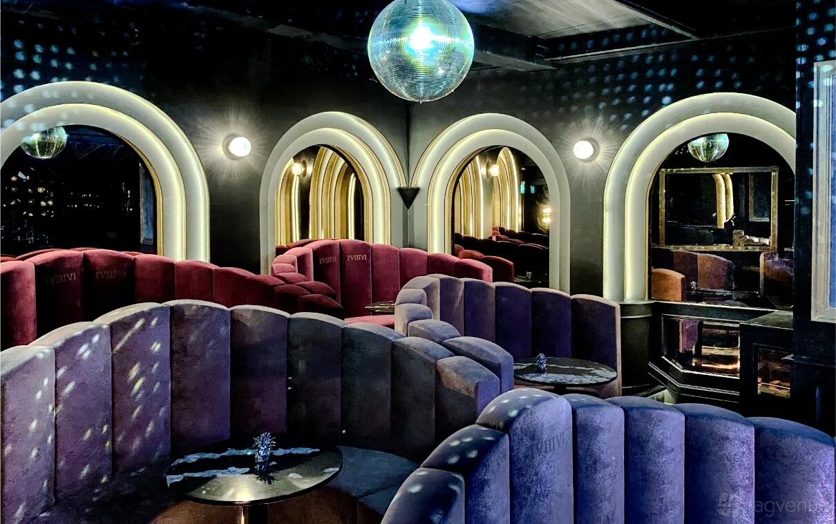 An event space in a bar with velvet curved booths, arched mirrors, and a disco ball at One Eight Six.