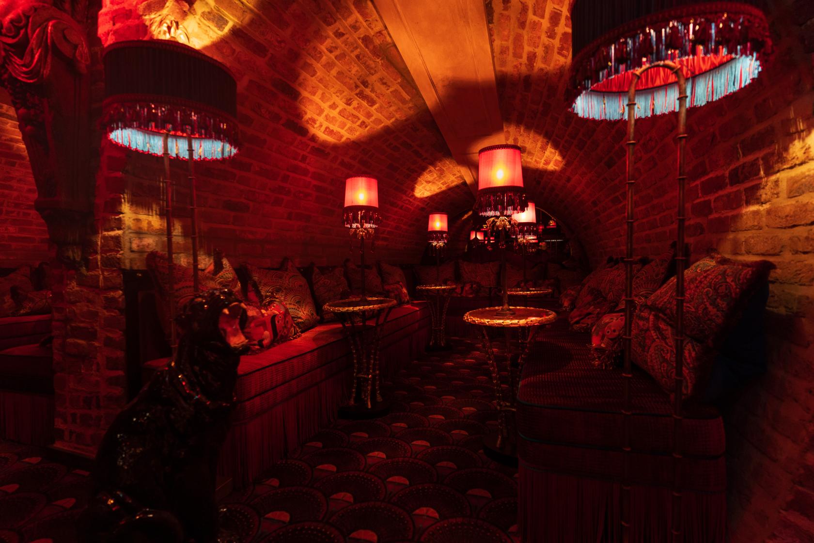 An event space in a cocktail bar with arched brick walls, plush seating, and red lanterns at Zum Barbarossa.