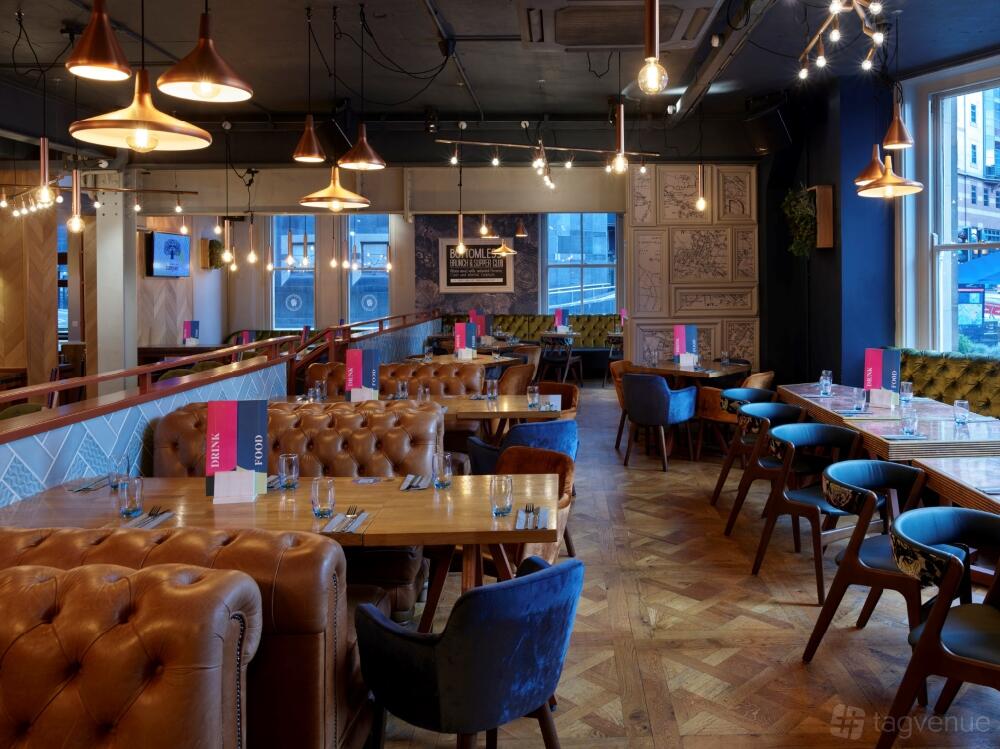 An event space in a bar with tufted leather seating, wooden tables, and large windows at Banyan Bar & Kitchen.