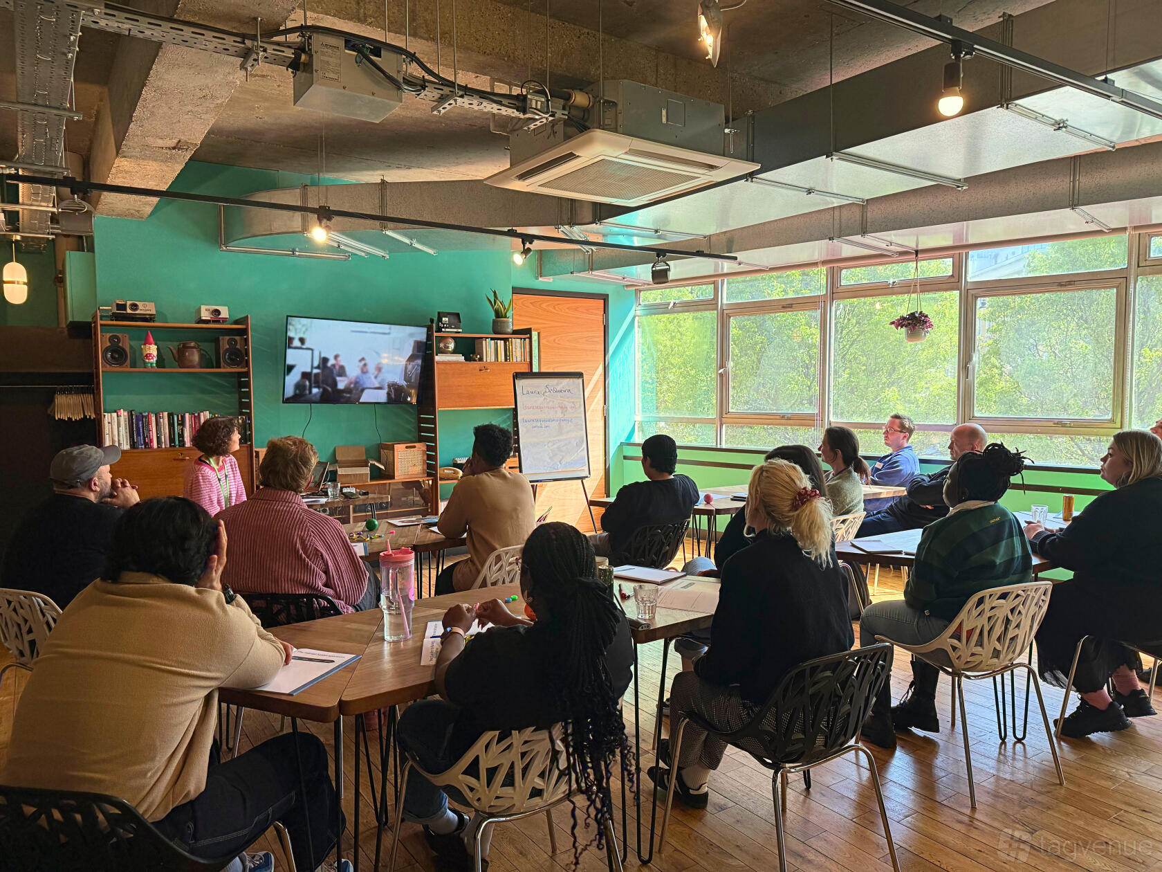 A library with large windows, natural light, and meeting tables with chairs at The Trampery Old Street.