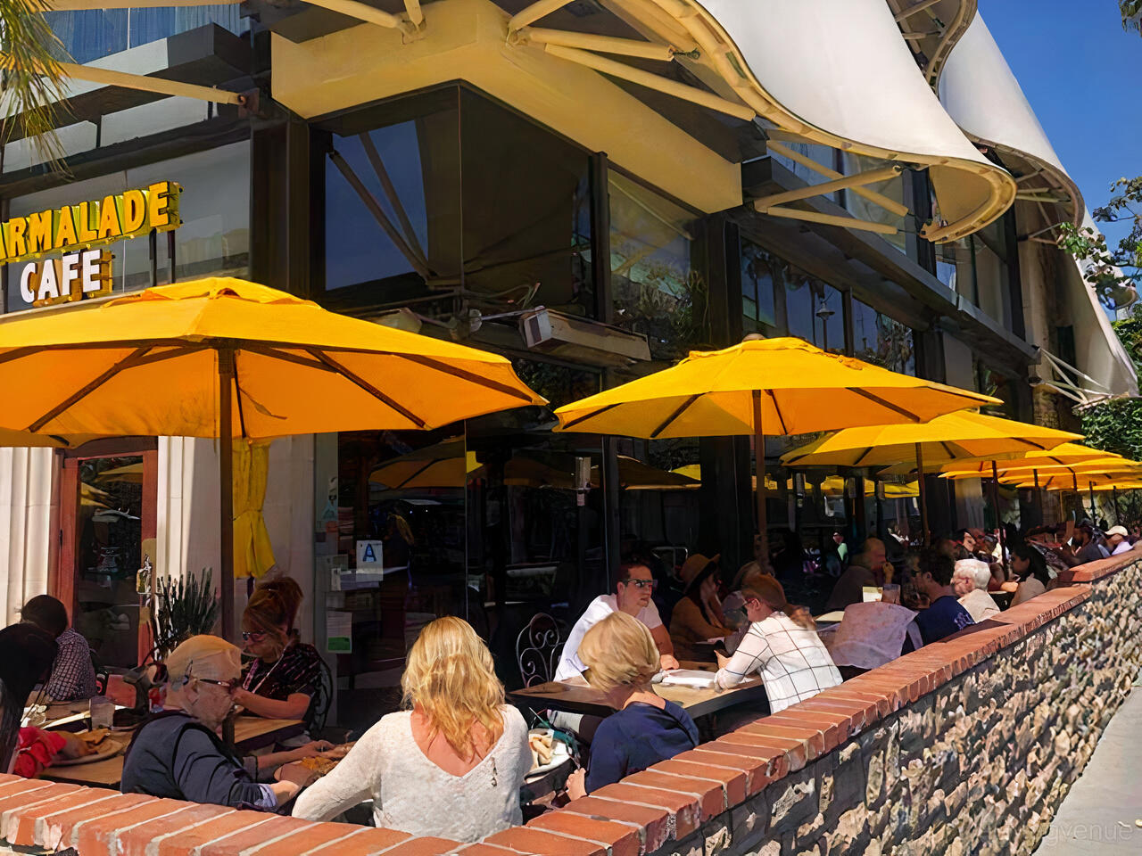 An outdoor dining area with yellow umbrellas and patio seating at Marmalade Cafe - Los Angeles.