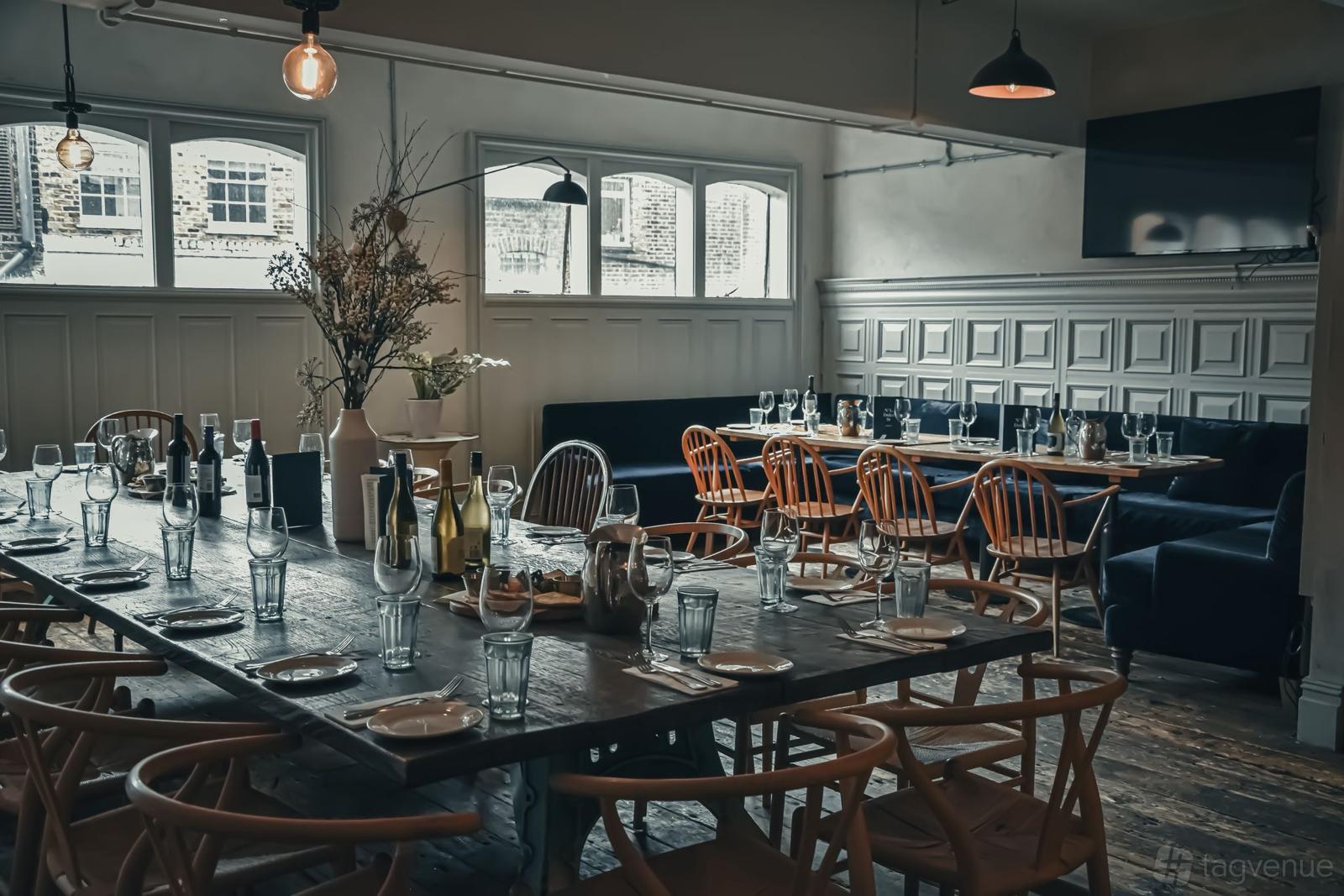 A dining room with wooden tables, patterned chairs, banquette seating, and large windows at No.1 Duke Street.