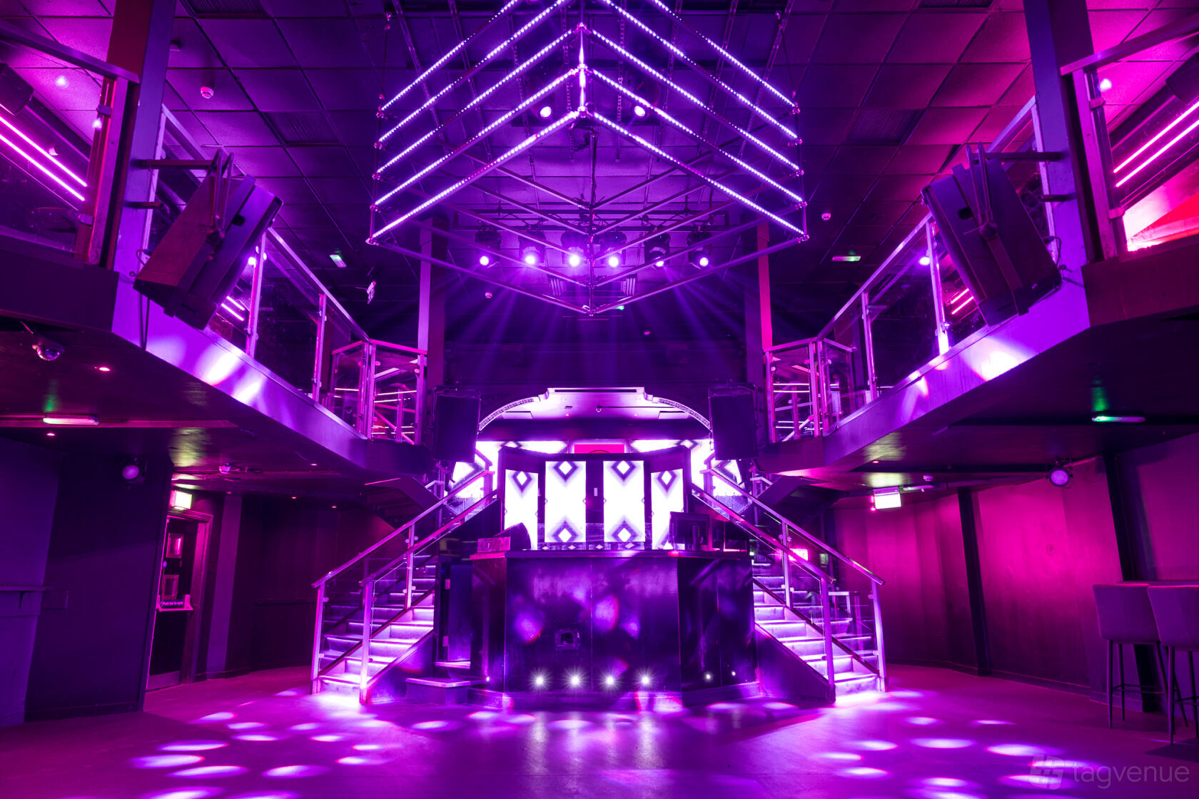 A nightclub event space with purple LED lighting, DJ booth, and dual staircases at Circuit York.
