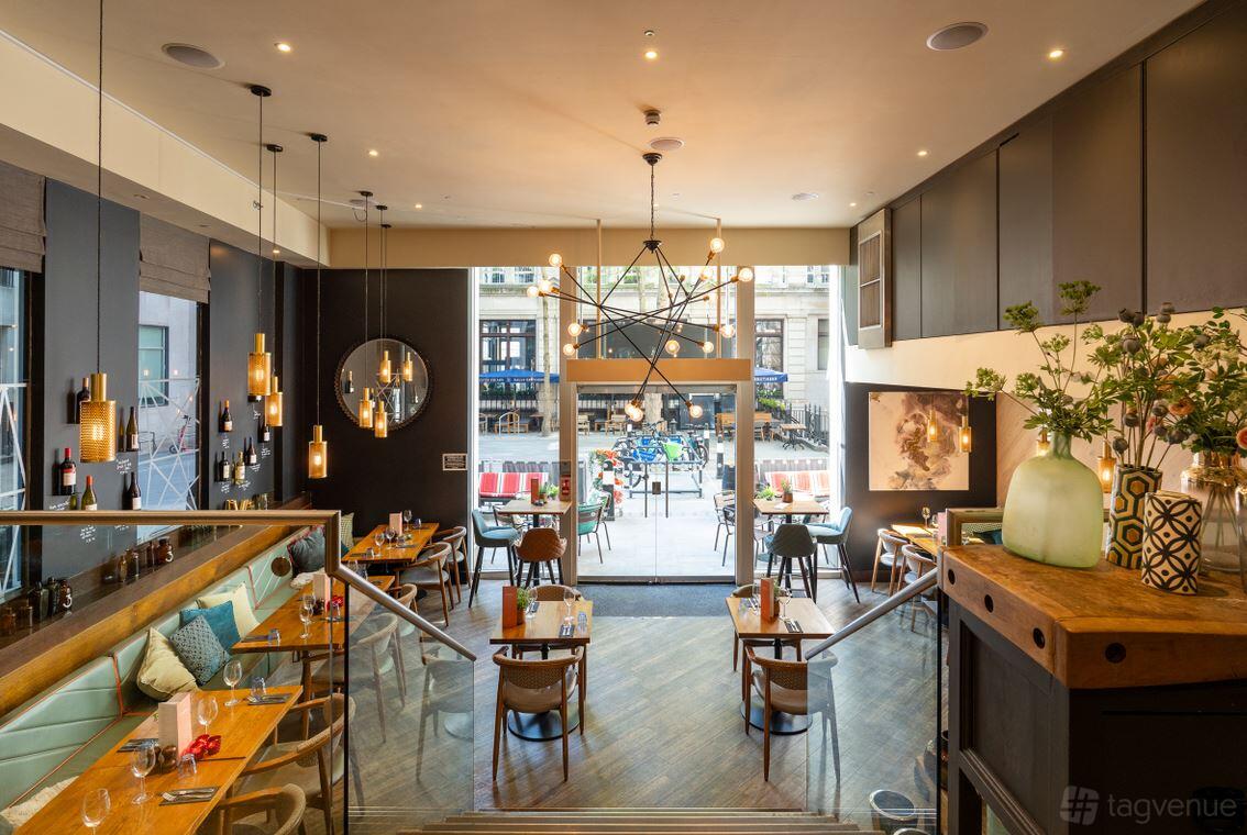 A cocktail bar with pendant lighting, wooden floors, and floor-to-ceiling windows at The Otherist.