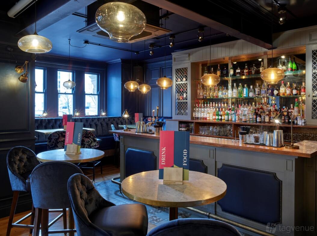 An event space in a bar with marble-topped tables, velvet chairs, and a backlit bar at Banyan Bar & Kitchen.