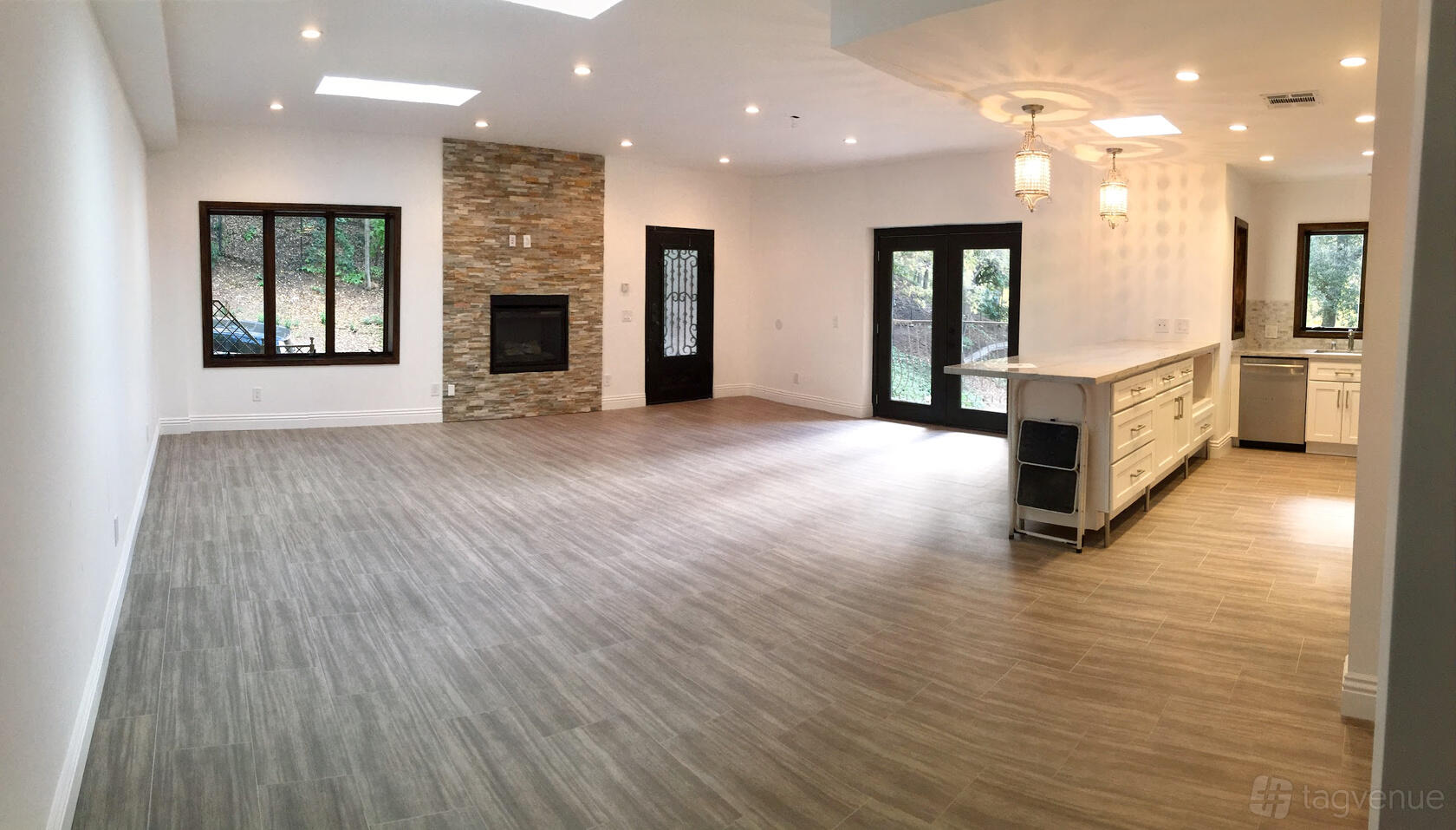 An open plan house space with wood flooring, skylights, a stone fireplace, and a large kitchen island at House 45.