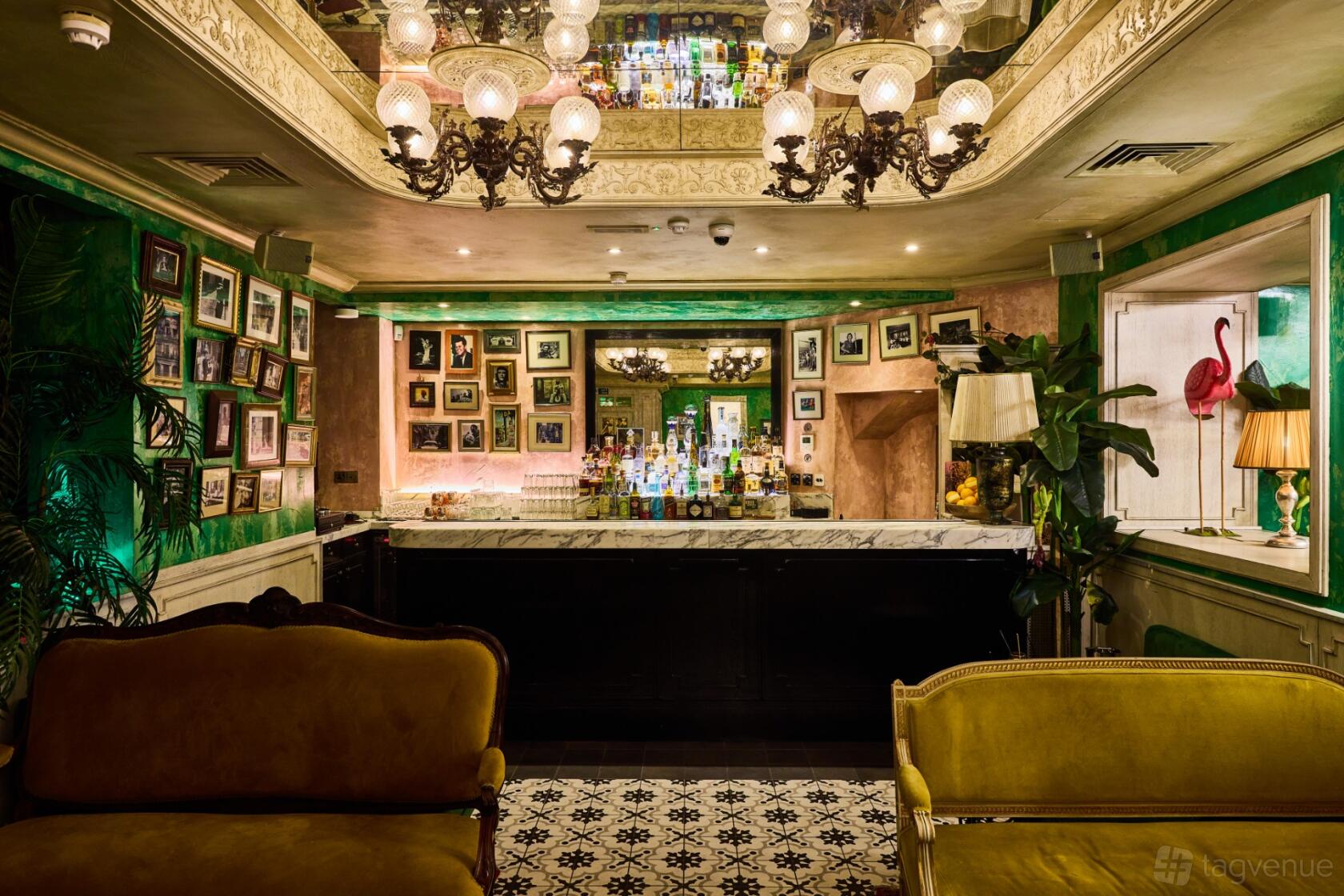 A bar with velvet sofas, a marble countertop, vintage chandeliers, and framed art at Socialista Lounge.