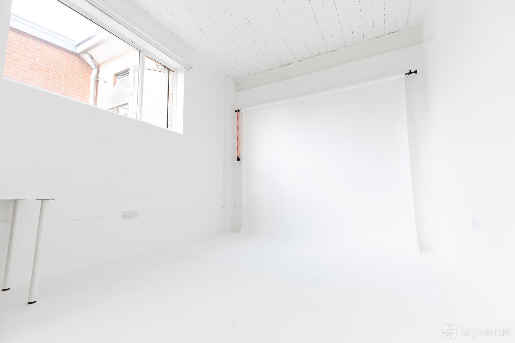 A photo studio with cyclorama walls, white floors, and large windows for natural light at Soif Studios.