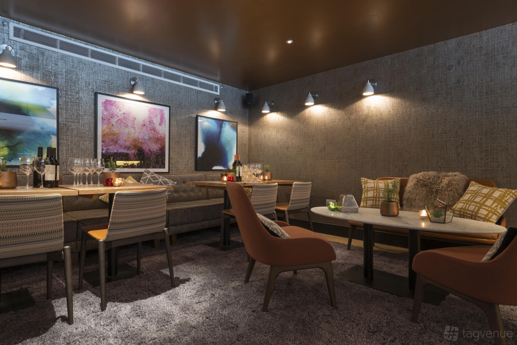 An event space in a restaurant with marble tables, upholstered chairs, plush carpeting, and modern art at The Refinery New Street Square.