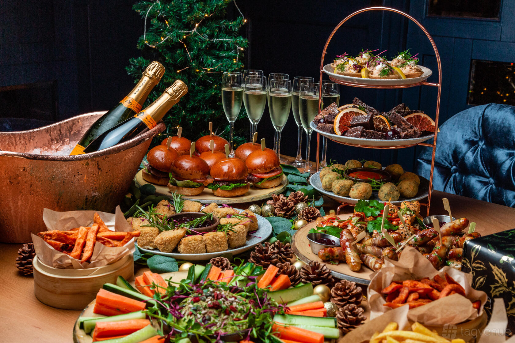 A dining room table with festive platters, mini burgers, champagne bottles, and glasses at Banyan Bar & Kitchen.