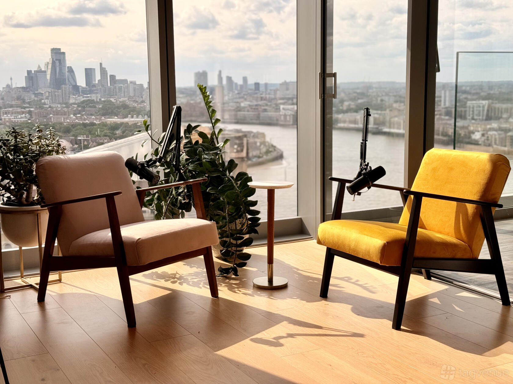 A TV studio with recording chairs, microphone arms, floor plants, and city views at Podcast Recording Studio.