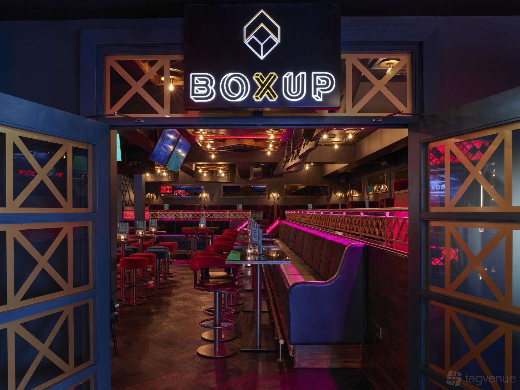 An event space in a bar with neon signage, booth seating, and pink accent lighting at Box Brindley Place.