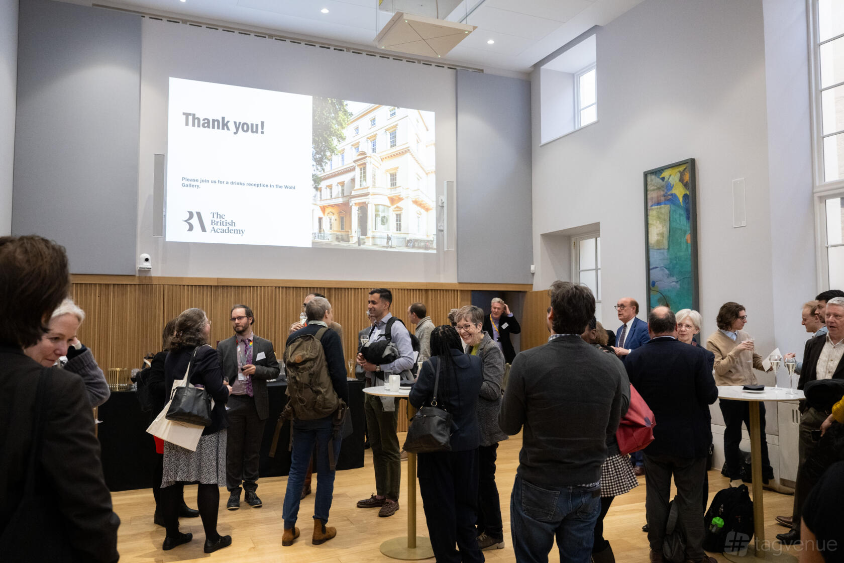 A function room with high ceilings, wooden floors, and a large projection screen at {10-11} Carlton House Terrace.