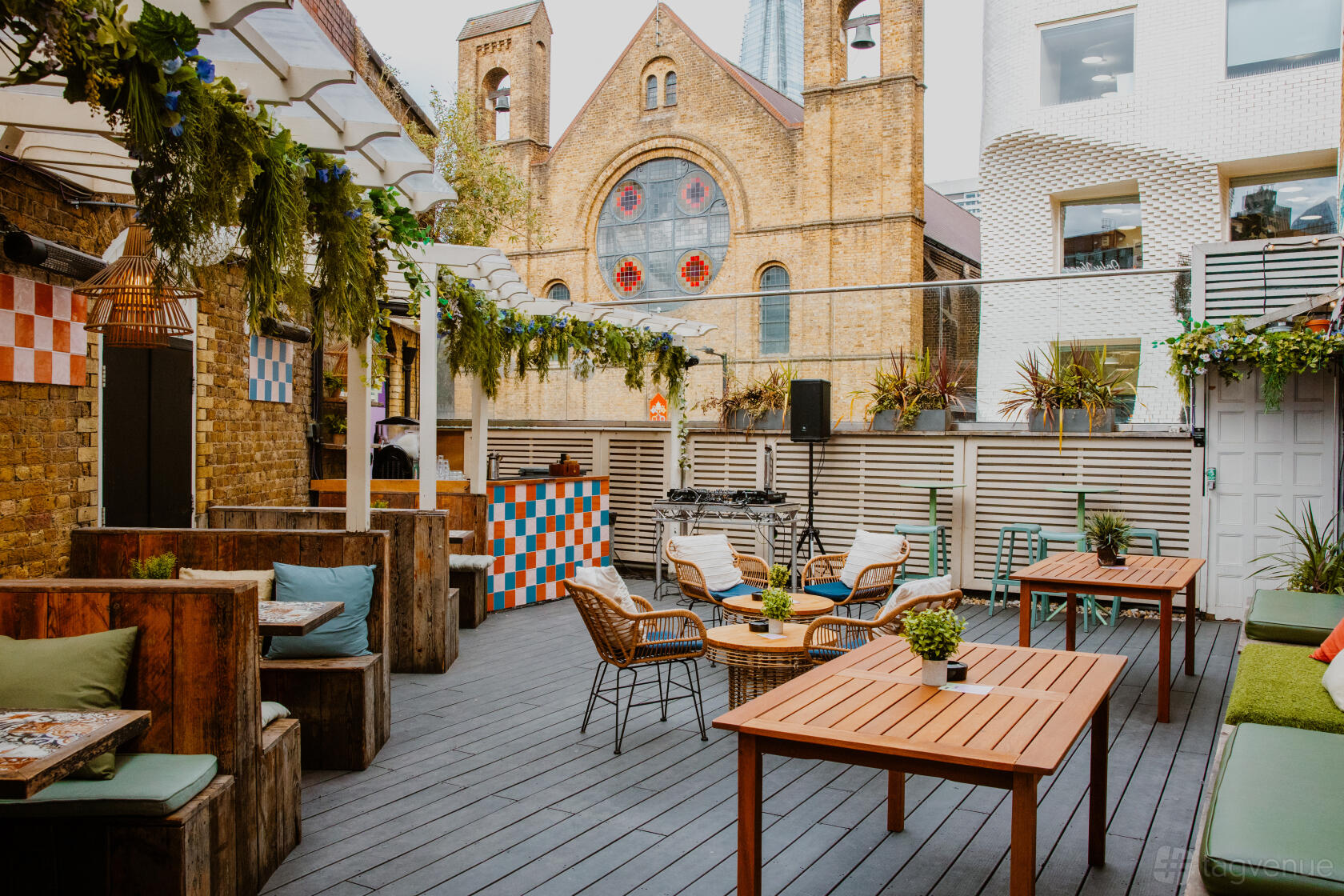 An open-air terrace with wooden tables, greenery, and rattan chairs at Omeara.