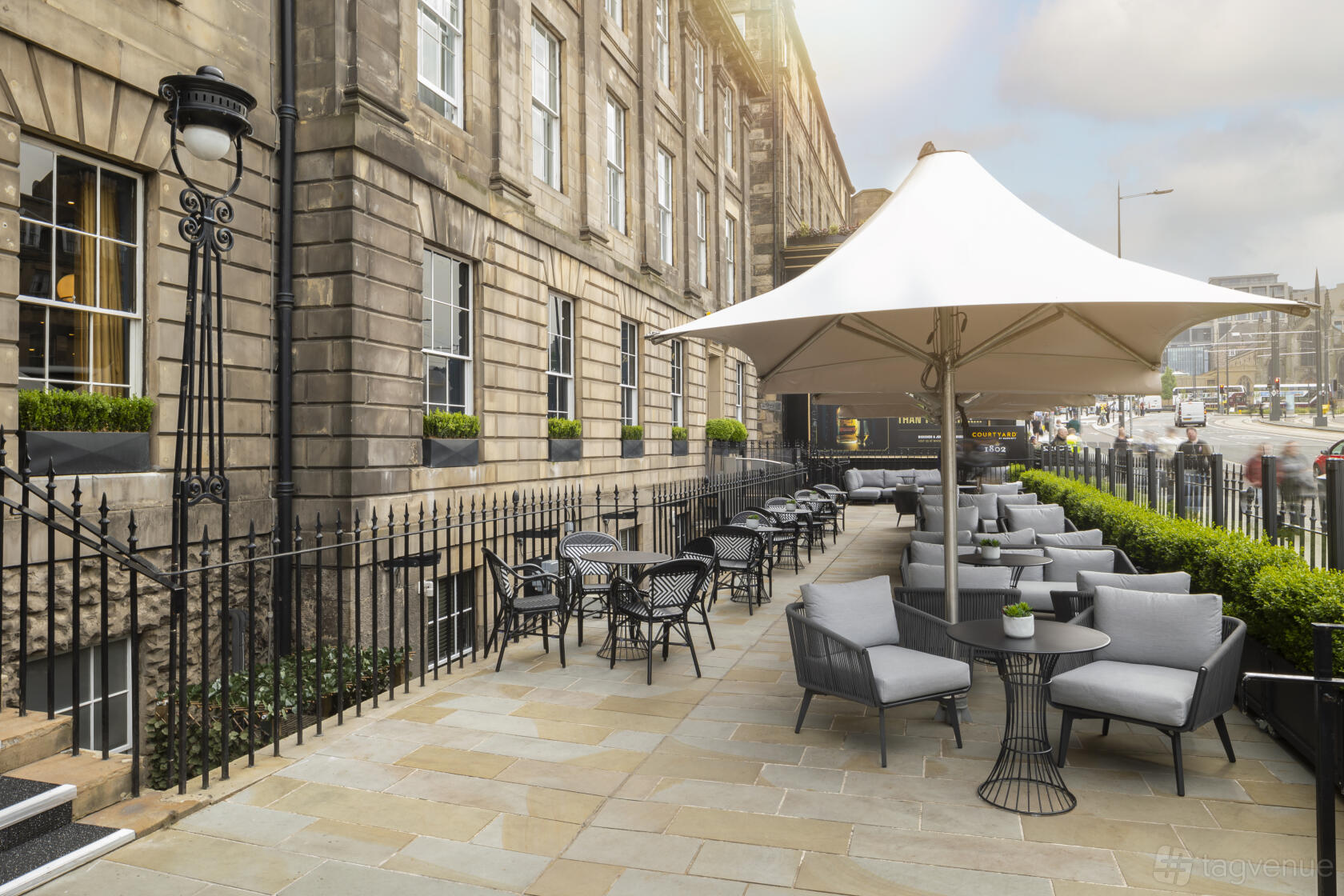 A hotel terrace with outdoor lounge seating, large umbrella, and stone paving at Courtyard by Marriott Edinburgh.