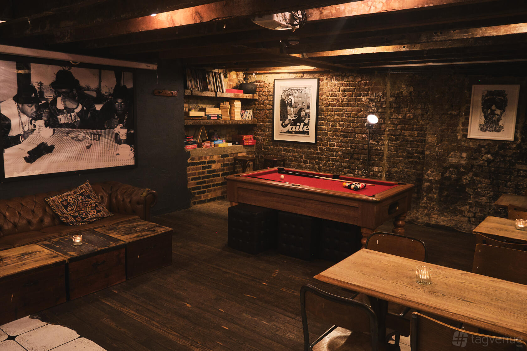 A function room with exposed brick walls, a red felt pool table, and wooden tables at The Gallery.