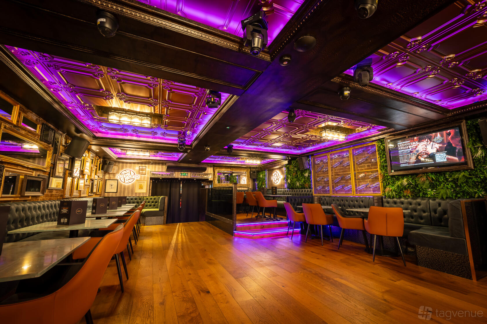 An event space in a bar with tufted banquette seating, mirrored walls, and purple ceiling lights at Soho Zebrano.