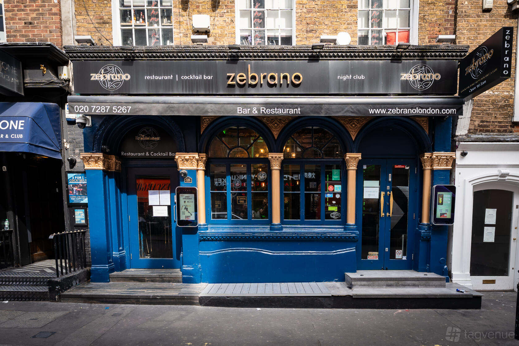 A restaurant and bar with a blue-painted exterior, arched windows, and branded signage at Soho Zebrano.