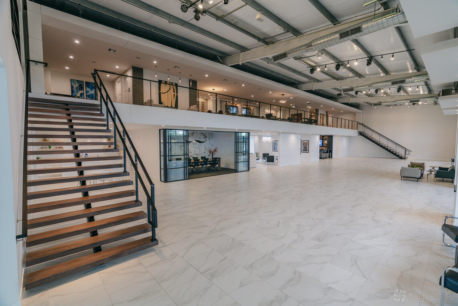 An event venue with high ceilings, open mezzanine level, marble tile flooring, and industrial lighting at The Brittmoore - Luxury Event Venue.