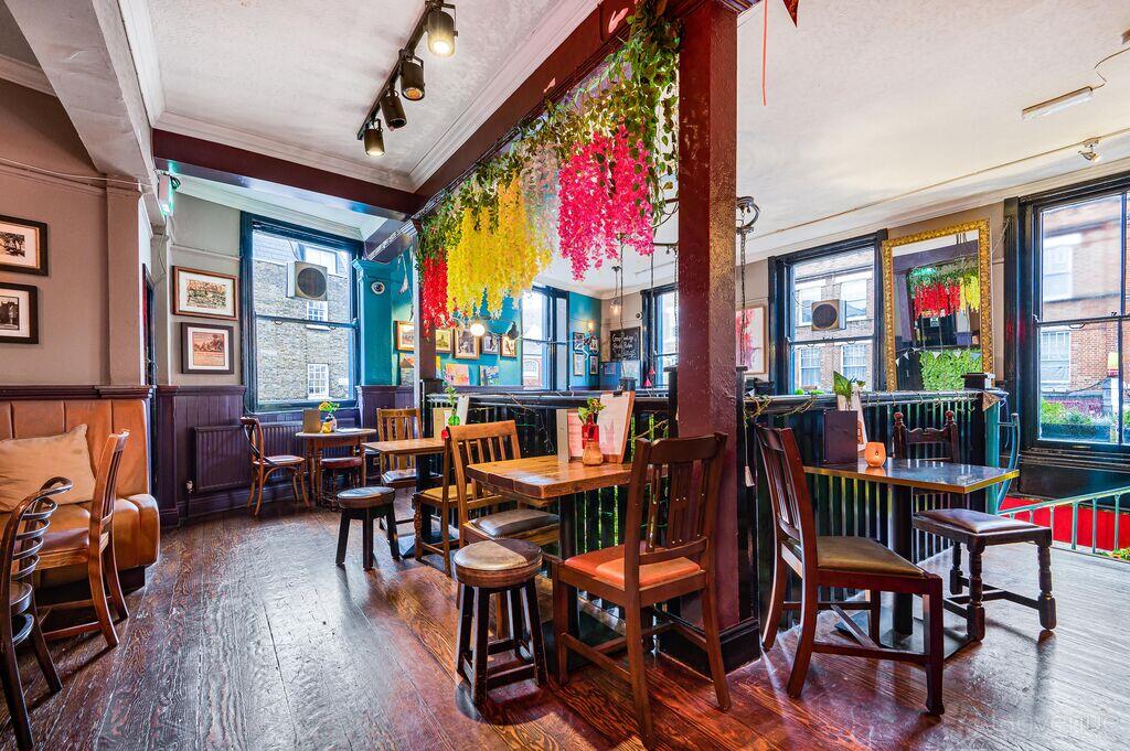 An event space in a pub with wooden floors, hanging floral decor, and large windows at The Bull.