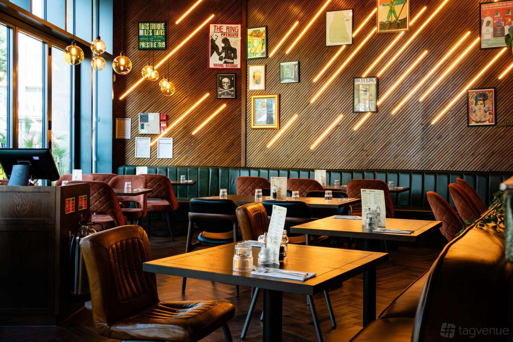 A dining room with wood panel walls, retro light fixtures, and framed artwork at Leadbelly's Bar & Kitchen.