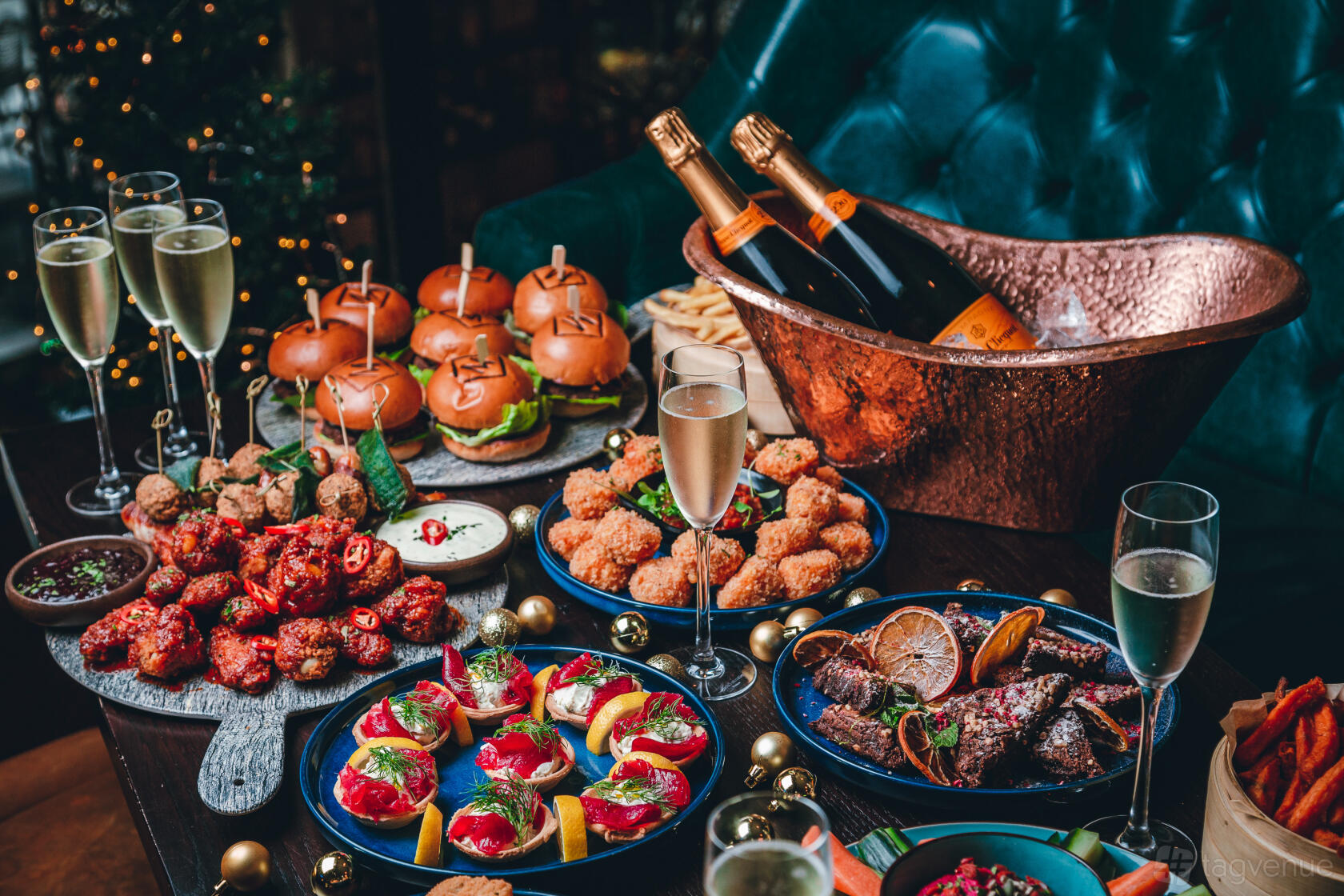A dining room table with sliders, fried appetizers, champagne bottles in a copper ice bucket at Manahatta Sheffield.