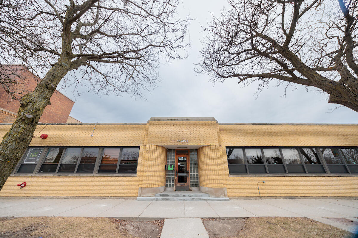 A coworking space with yellow brick facade, wide windows, and a central entrance at Platform Coworking.