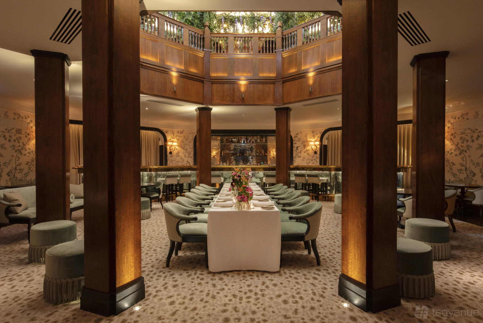 A hotel dining room with a long formal table, upholstered chairs, wood columns, and a domed balcony at L'oscar London.