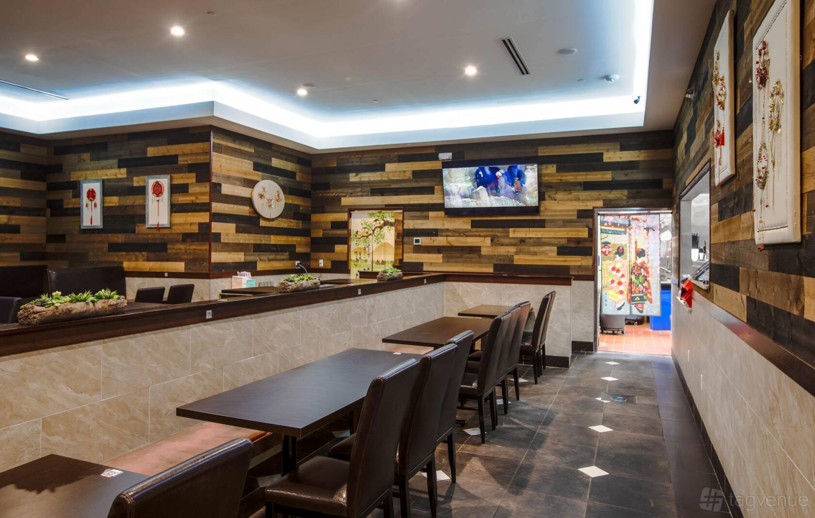 A restaurant dining room with dark wood tables, leather chairs, and wood plank accent walls at Xian @ San Marcos.