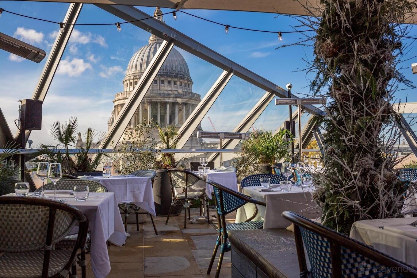 A bar in a restaurant with glass walls, white-clothed tables, and views of a domed landmark at Madison.