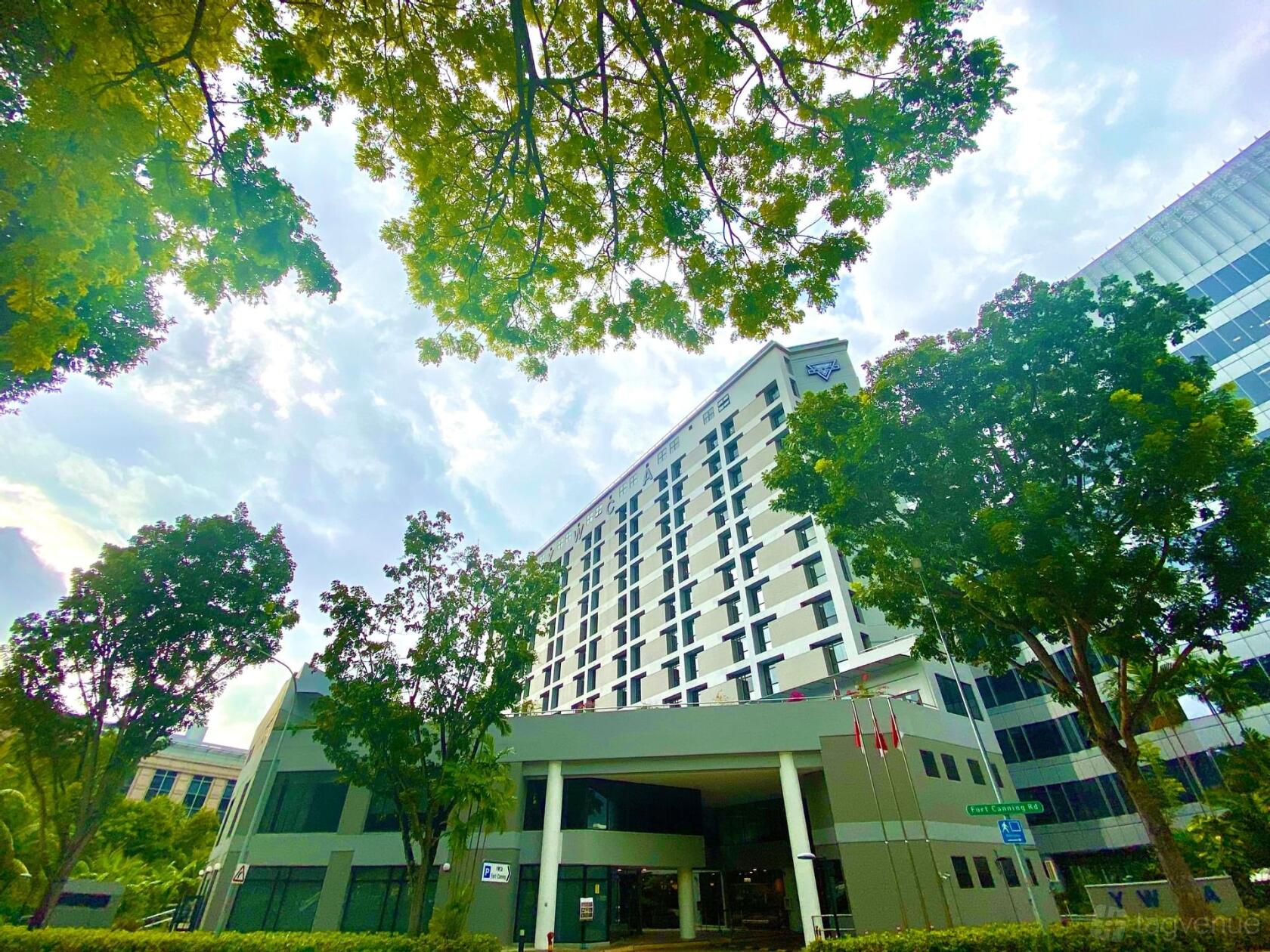 A hotel exterior with tall windows, flagpoles, and surrounding trees at Sophia Cooke Ballroom.