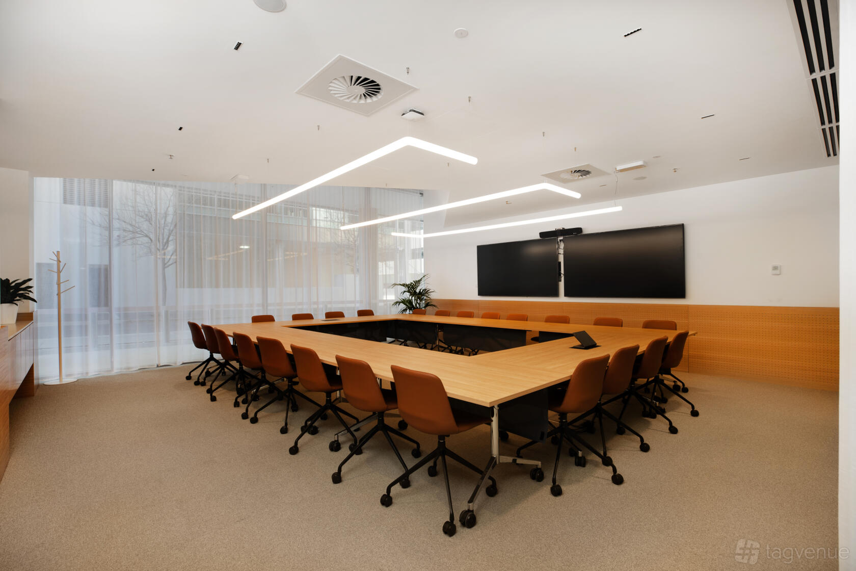 A meeting room with a large U-shaped table, ergonomic chairs, floor-to-ceiling windows, and double display screens at Flex by ISPT Pathway Place.