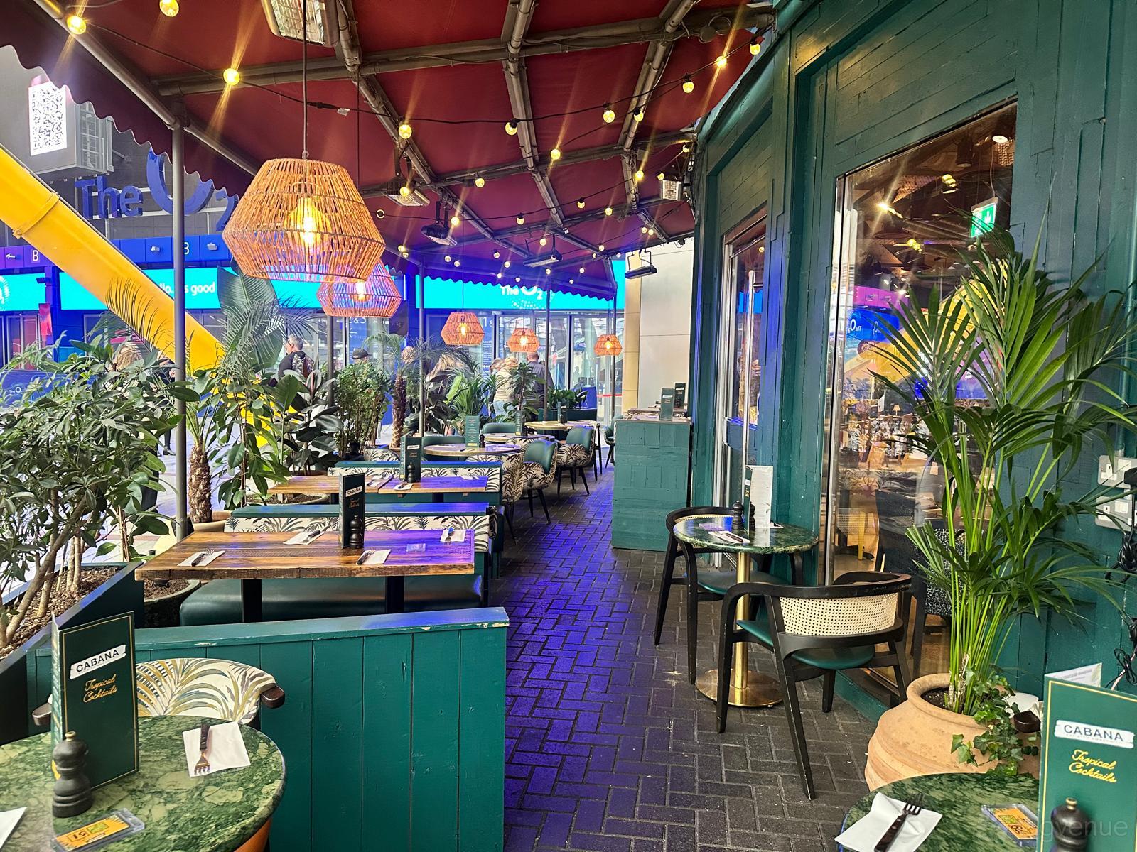 An event space at Cabana with woven pendant lights, potted plants, and teal accents on The Terraço at The O2.