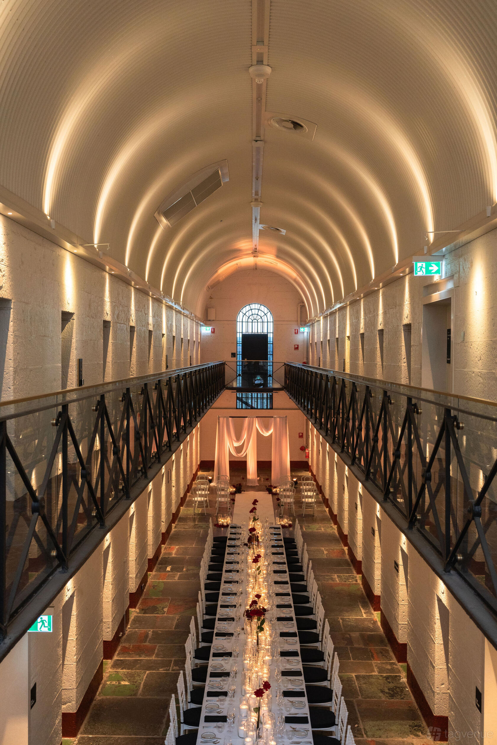 A hotel hall with arched uplighting, exposed stone walls, and glass railings at Chapter Place.