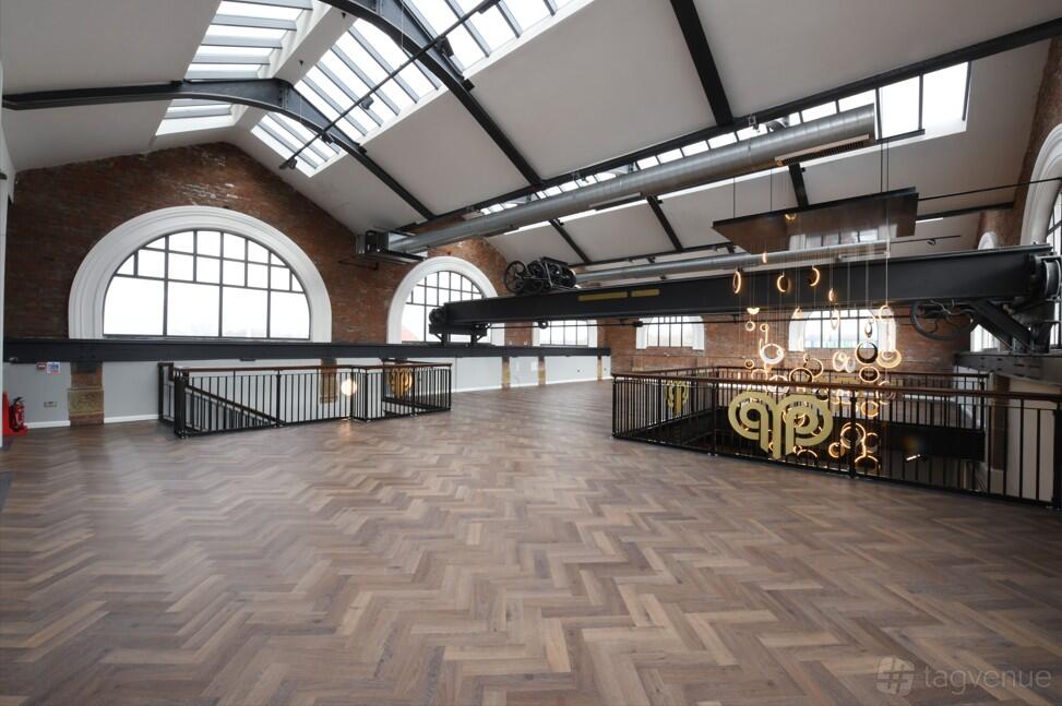 A photo studio with large arched windows, skylights, exposed brick walls, and herringbone wood floors at Heritage 1907- Ram Mill.