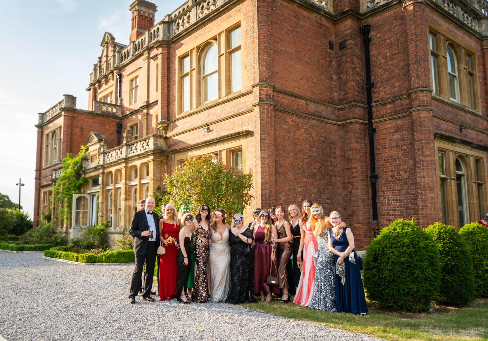 A stately brick hall with tall windows and manicured hedges at Rossington Hall.