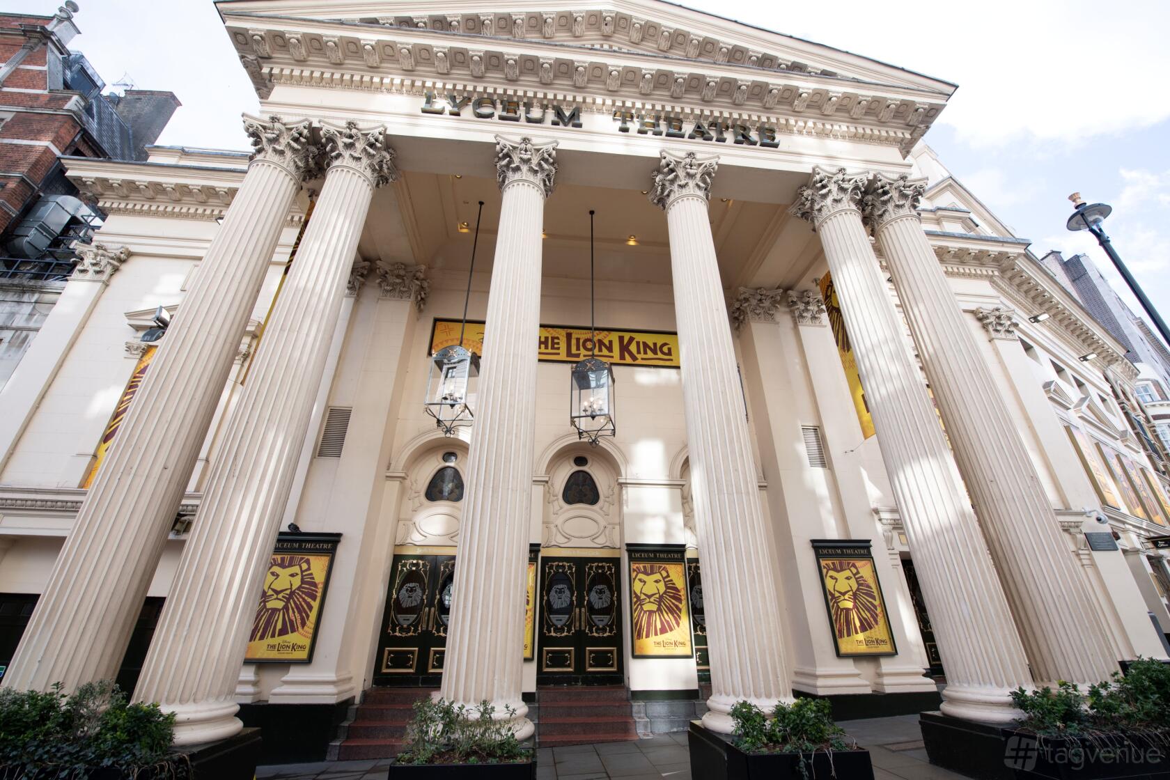 A theatre exterior with grand columns, ornate facade, and Lion King banners at ATG VIP: The Lion King - Lyceum Theatre.