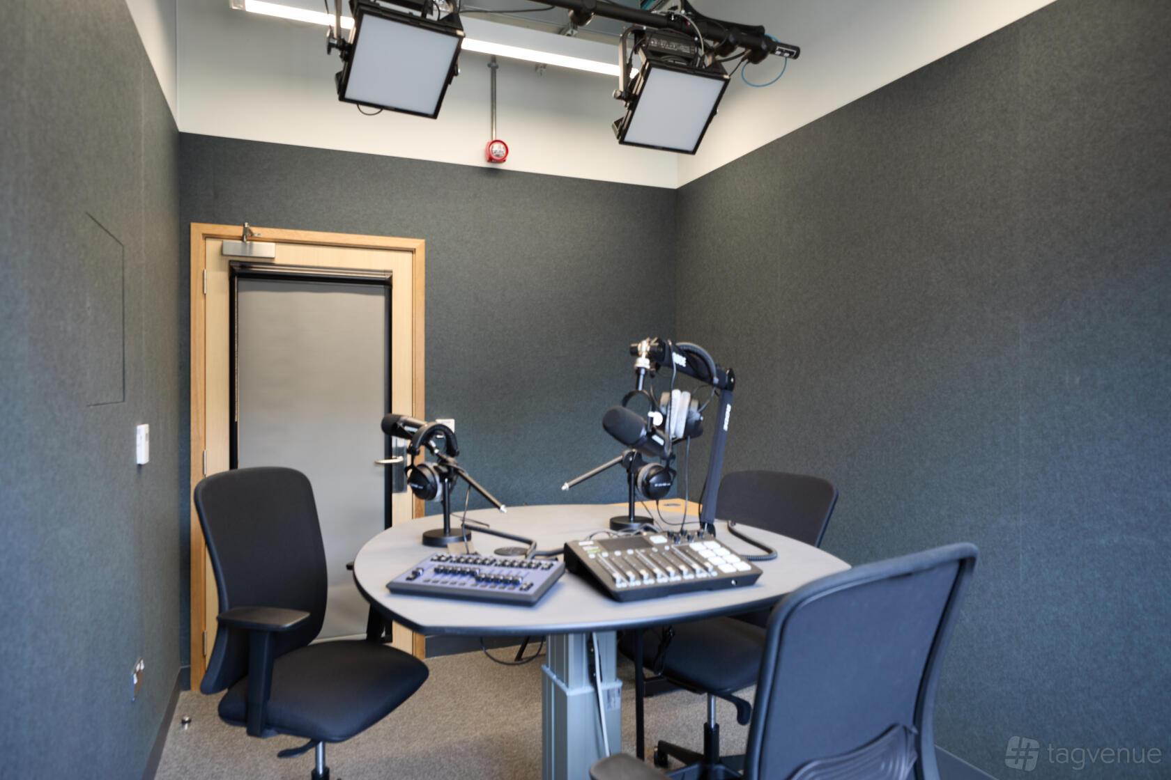 A podcast studio with soundproofed walls, recording microphones, and a mixing desk at SOHO Centre.
