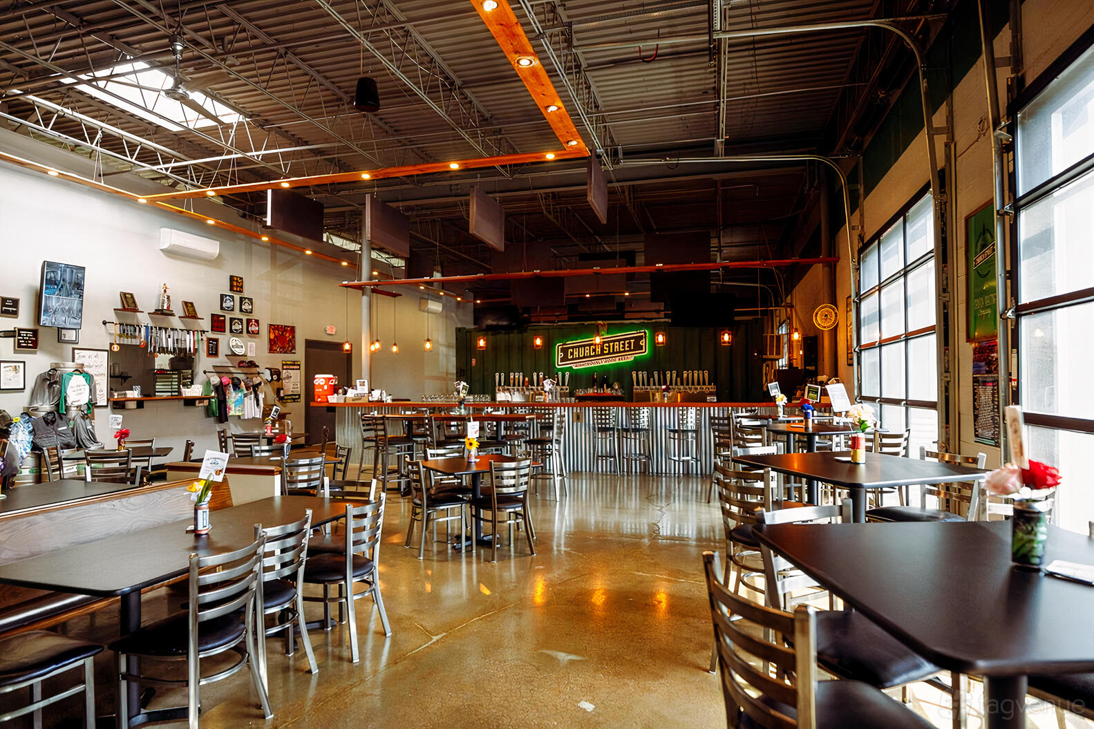 A brewery with polished concrete floors, high ceilings, wall art, and a large bar with tap handles at Church Street Brewing Company.