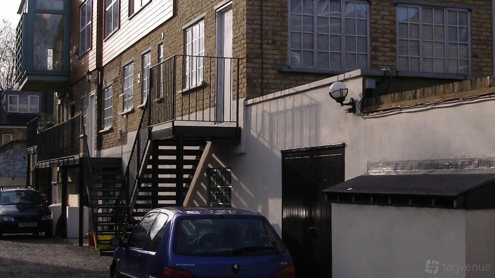 A converted warehouse venue with brick walls, large industrial windows, and an exterior staircase at Bedlam Loft Studio.