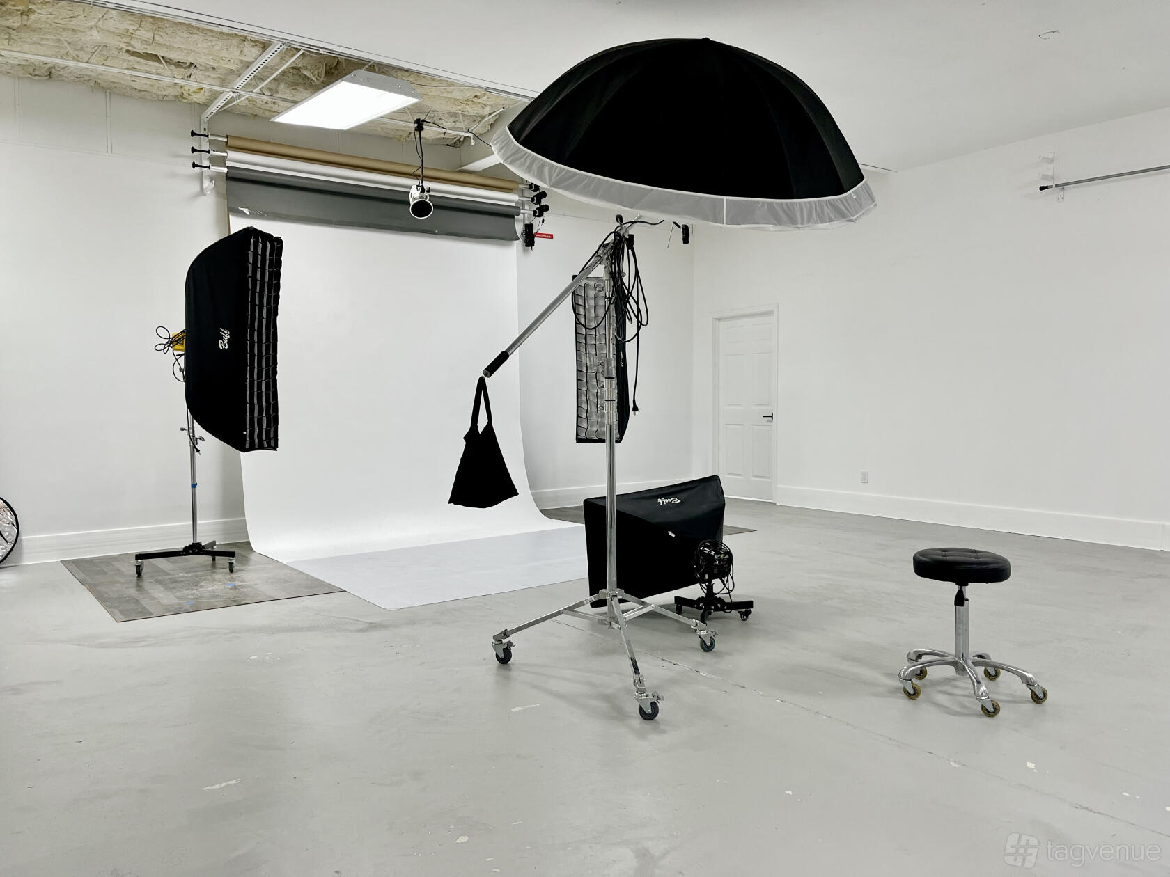 A photo studio with seamless white backdrop, softbox lighting, and photography equipment at CoLab Production House.