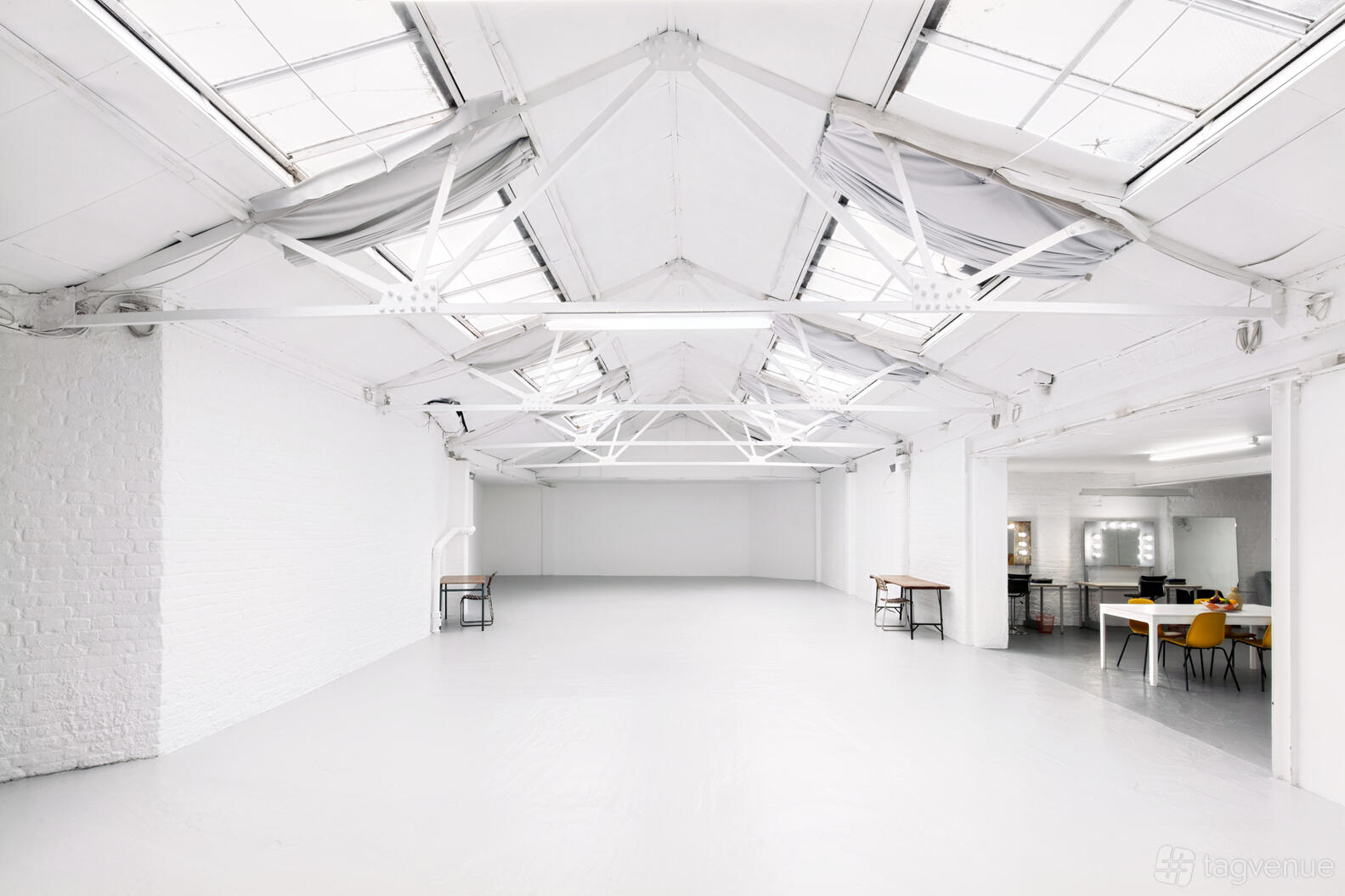 A photo studio with high ceilings, skylights, white walls, and exposed beams at Dalston Pier Studio.